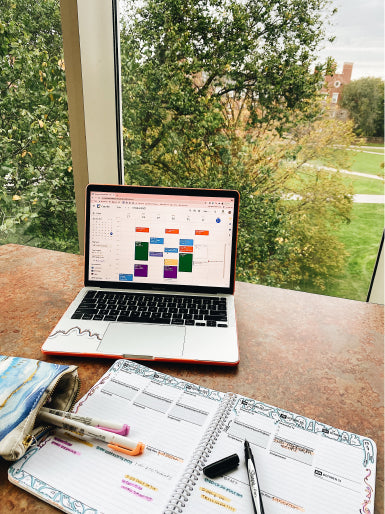 desk in front of a window with a laptop and student planner.
