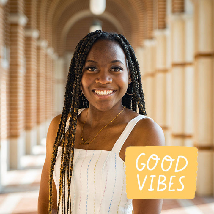 Smiling female student in a hallway with words Good Vibes.